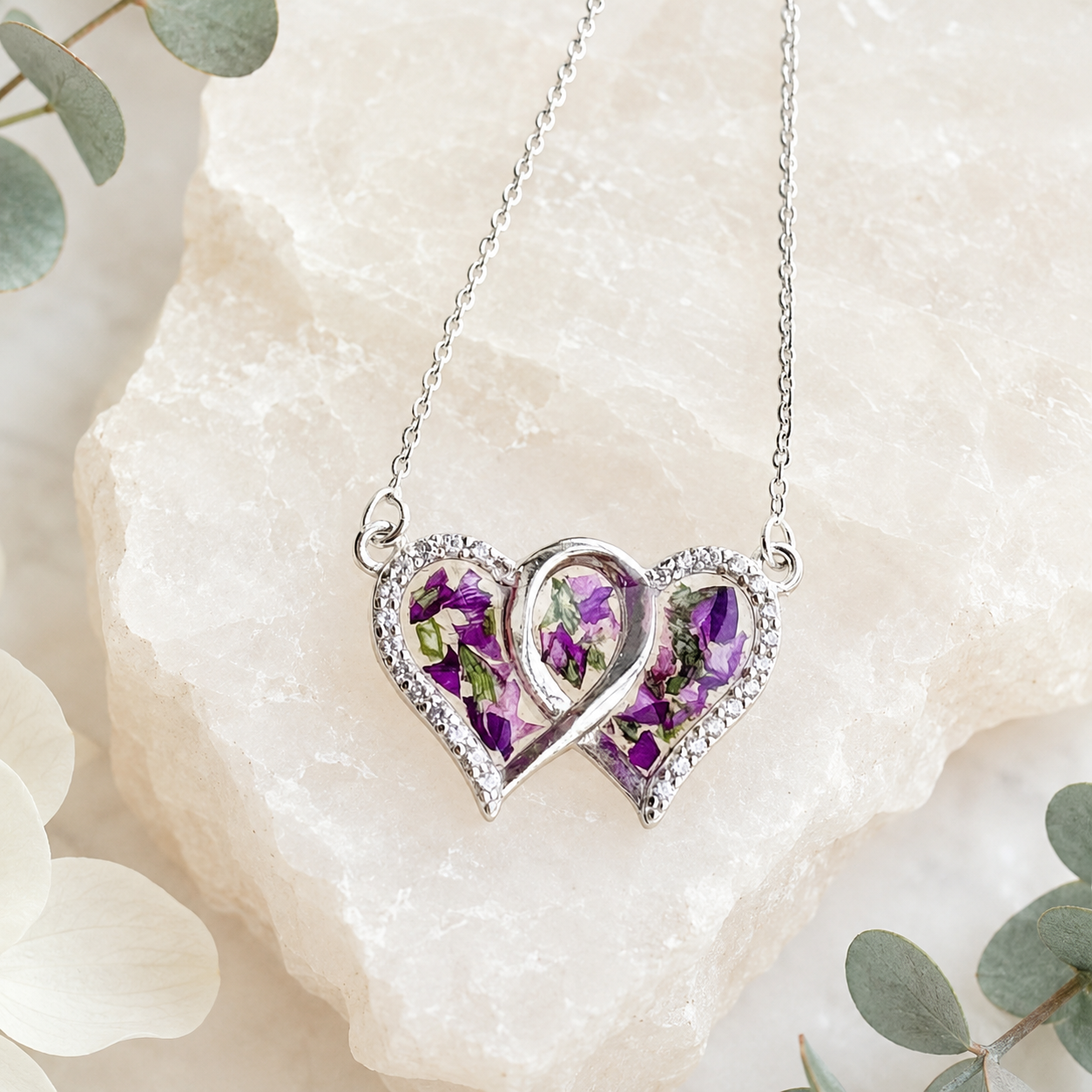 Infinity Heart Pendant with purple preserved flowers in a silver double-heart design.