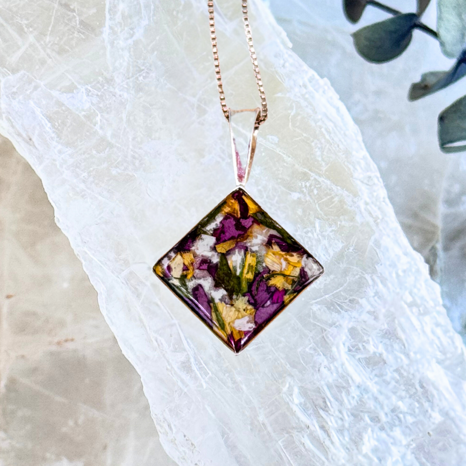 Front view of diamond-shaped pendant with preserved wedding and funeral flowers in sterling silver setting