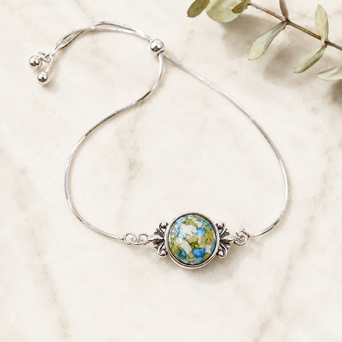 Fleur de Lis Heirloom Bracelet with blue, white and green preserved flowers in a silver setting.