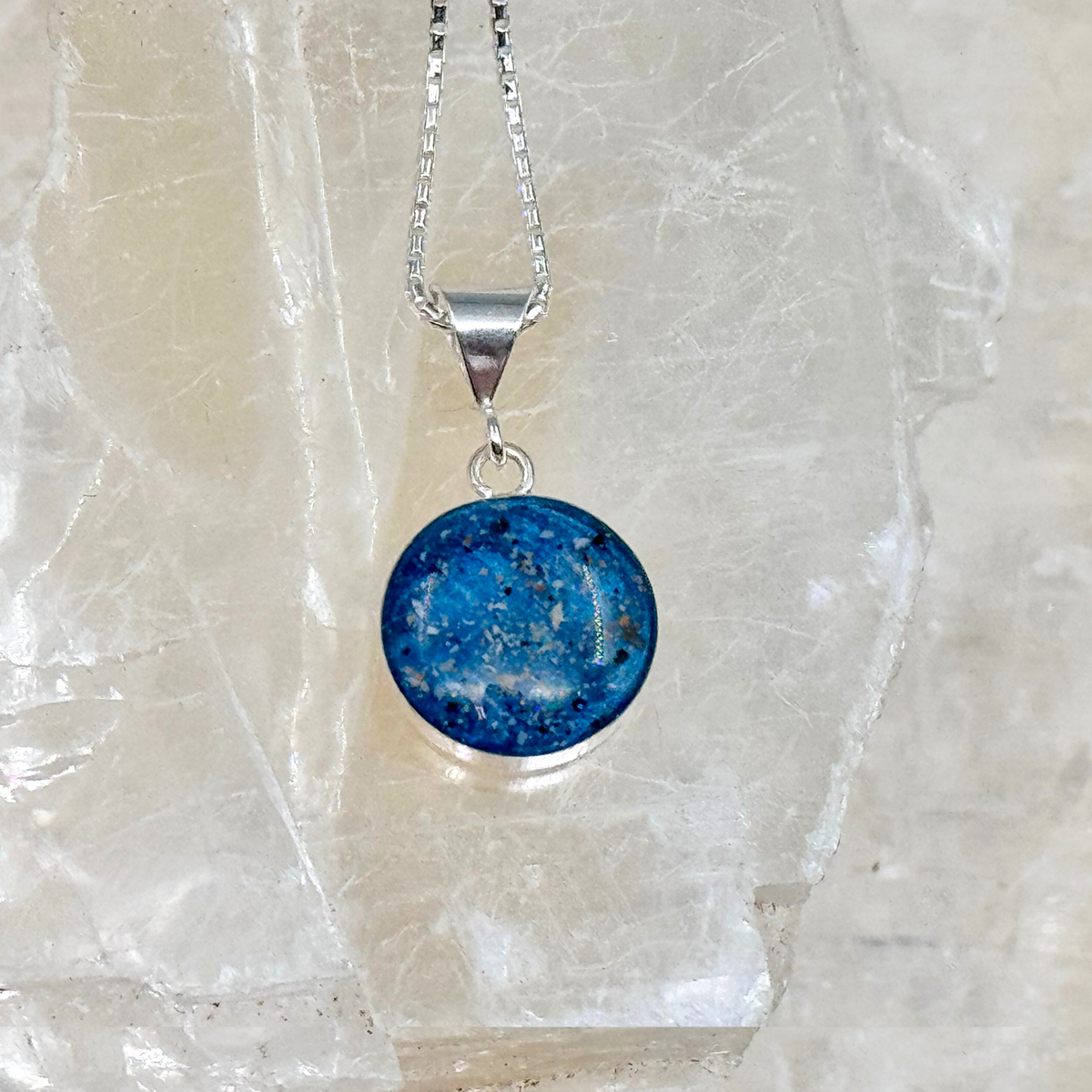 Close-up of the Loyal Companion round pet memorial ash pendant, showing fine detail, color depth, and the shimmer of silver or gold flakes.