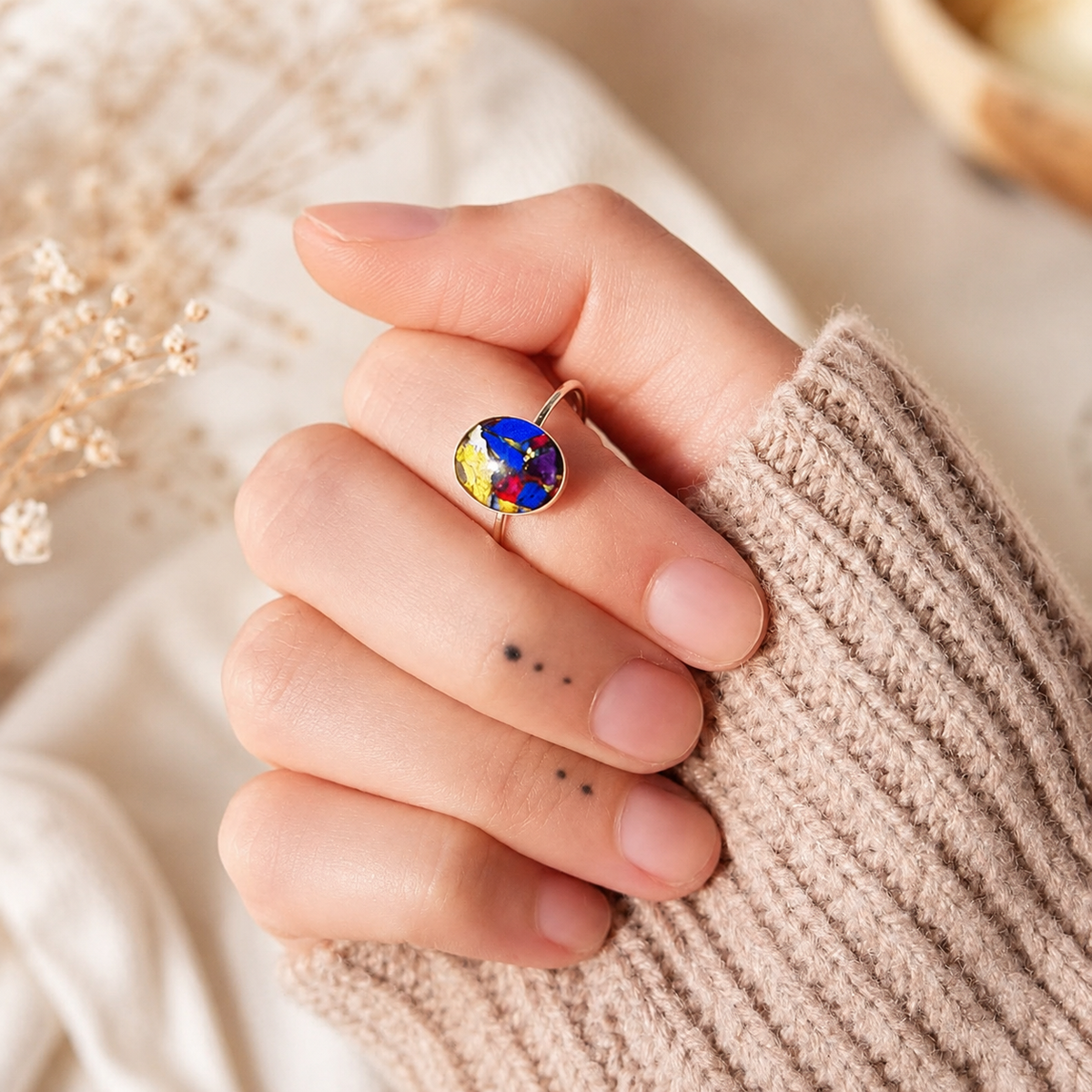 Model wearing Luna Bloom Ring with colorful preserved flowers in a gold setting.