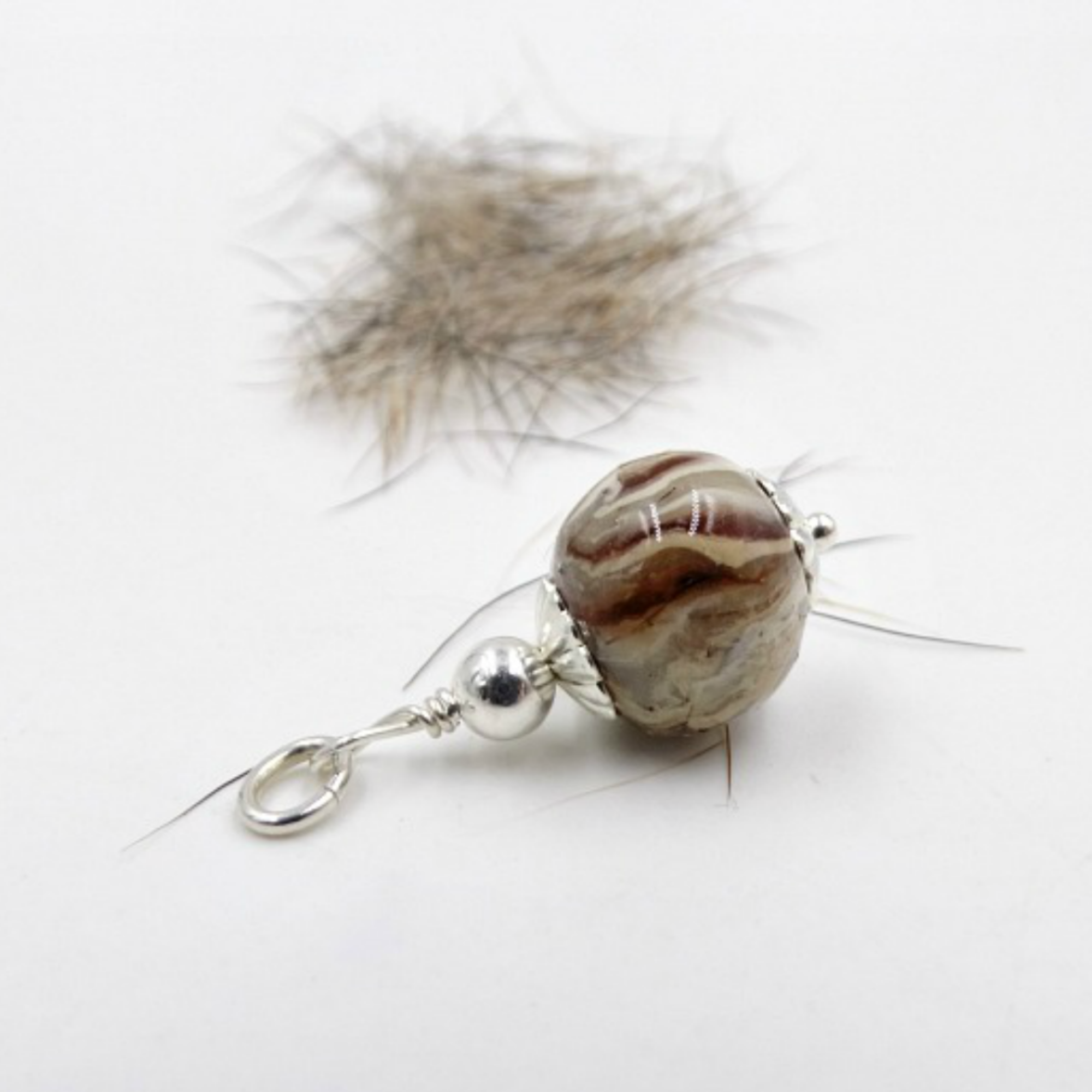 A handcrafted pet memorial charm made with pet fur, displayed alongside the fur used in its creation.