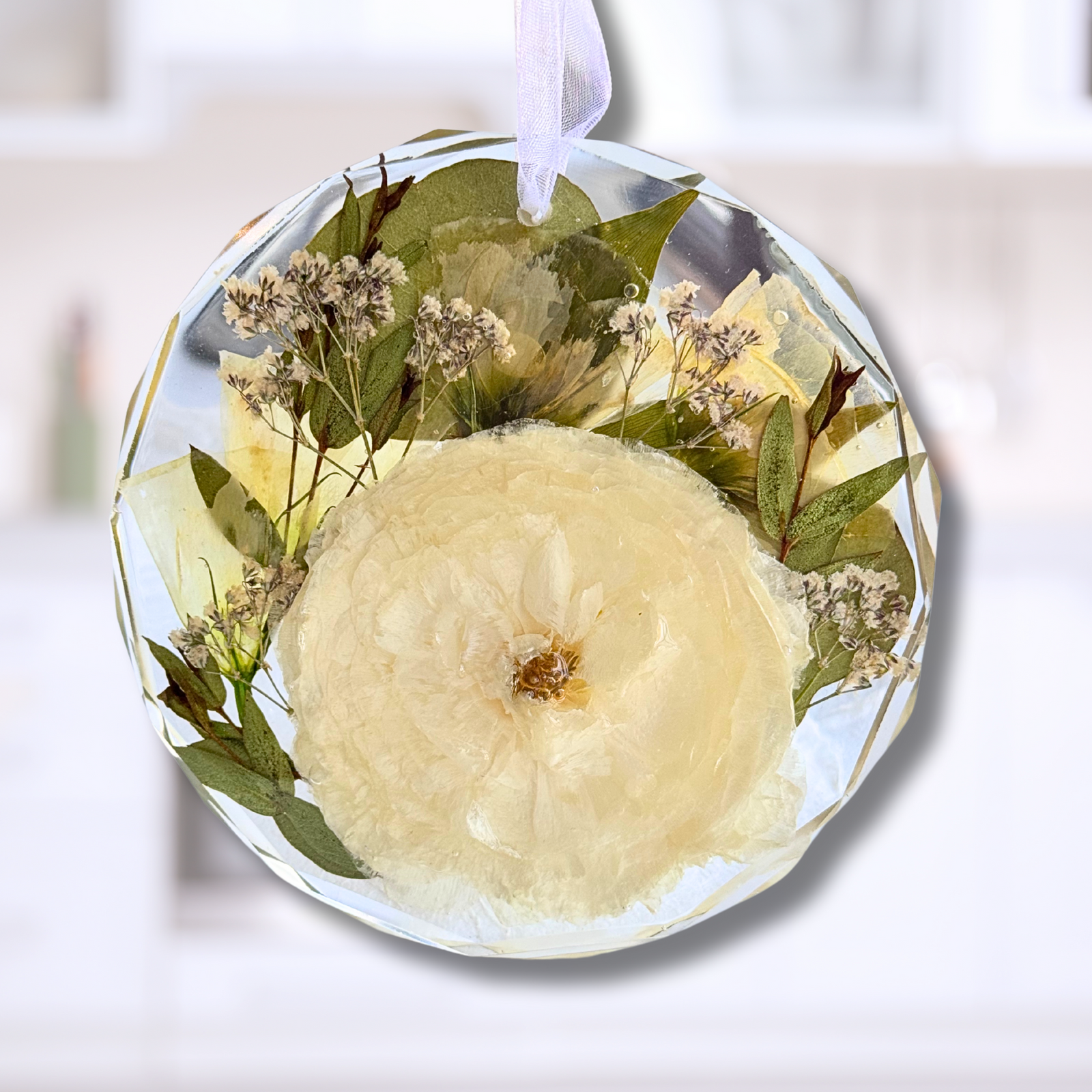 Resin ornament with preserved white ranunculus and greenery, handcrafted as a custom floral keepsake.