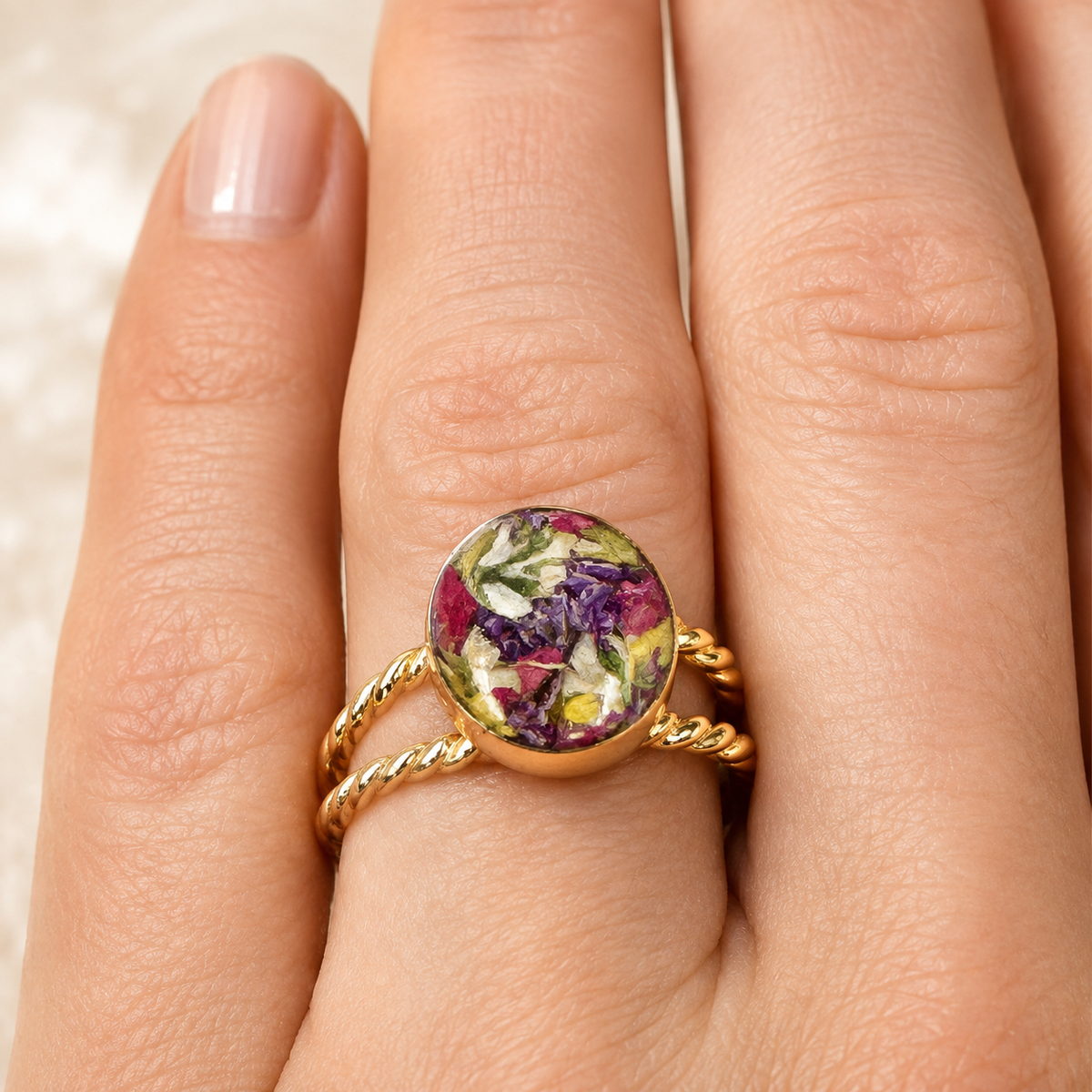 Model wearing Rosevine Keepsake Ring with colorful preserved flowers in a gold setting.