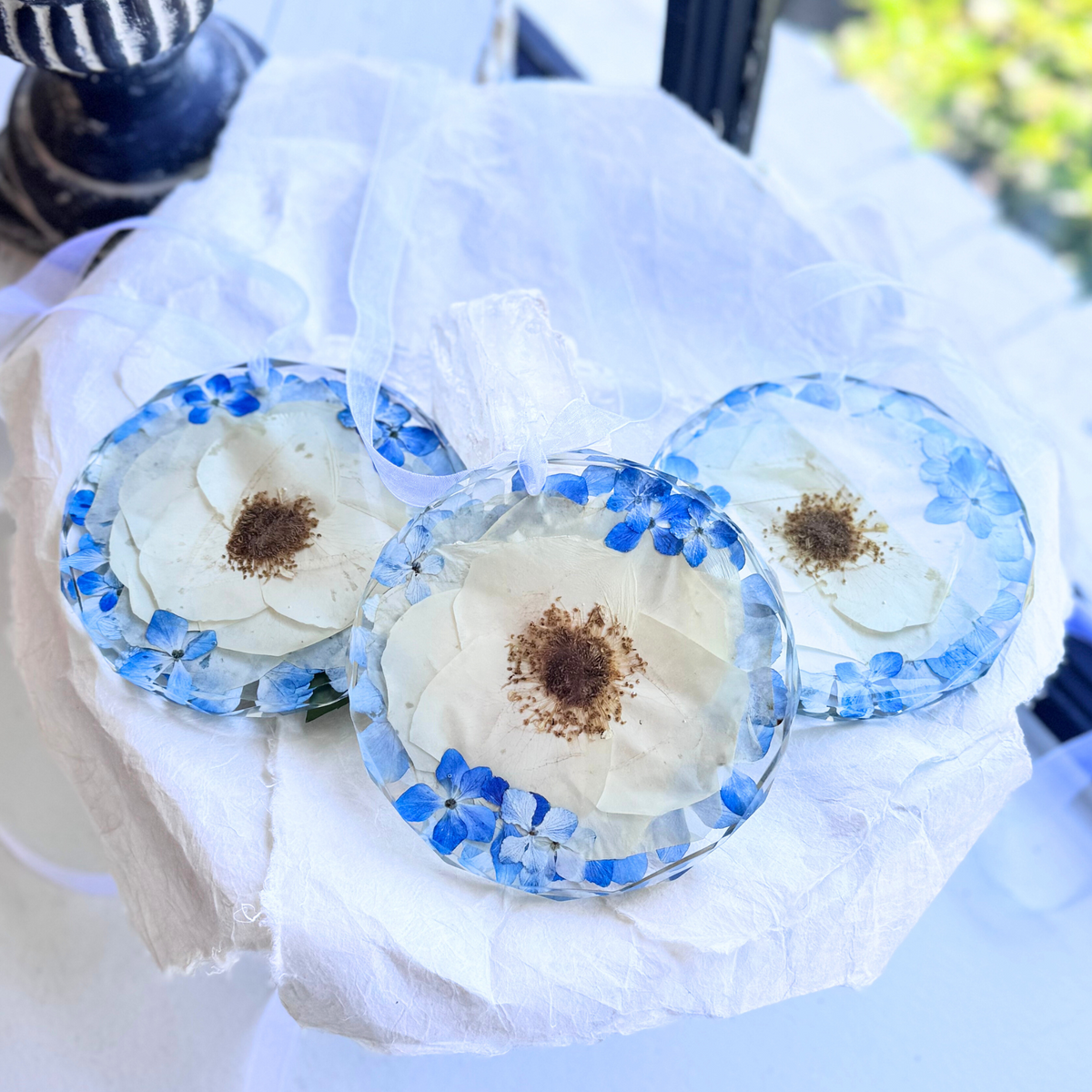 Set of round resin ornaments with preserved white flowers and blue hydrangeas, handmade keepsakes from wedding or memorial bouquets