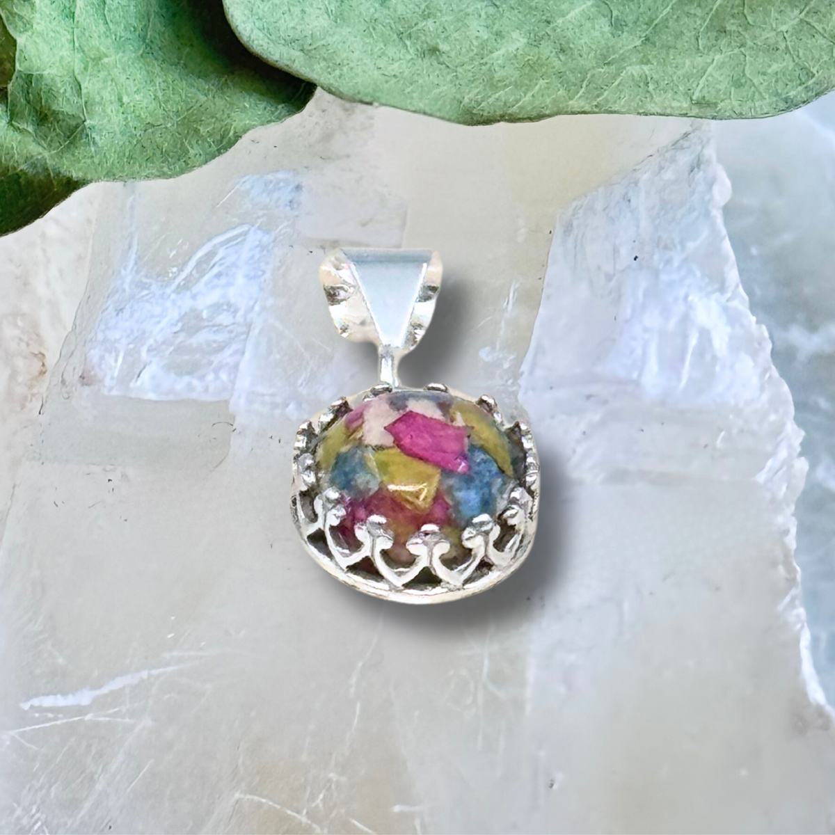 Side view of resin pendant with colorful preserved flower petals in ornate silver crown setting, custom memorial or wedding keepsake