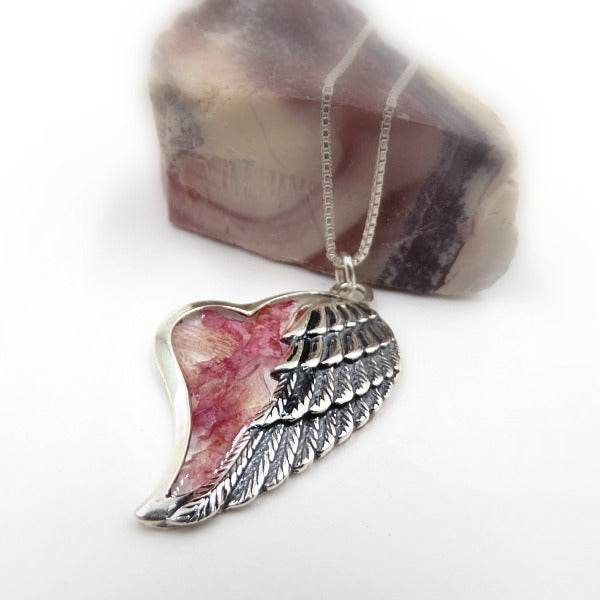 Side view of the Angel's Embrace Pendant, highlighting the angel wing design wrapped around preserved flowers.