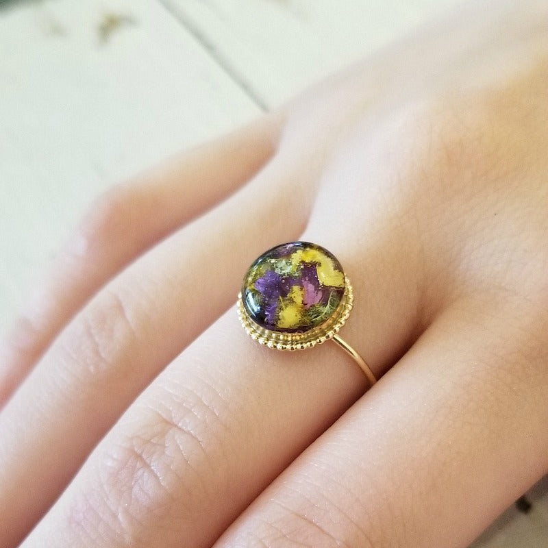 Gold-plated Circle of Memories Ring displayed on top of preserved flowers used in its design.
