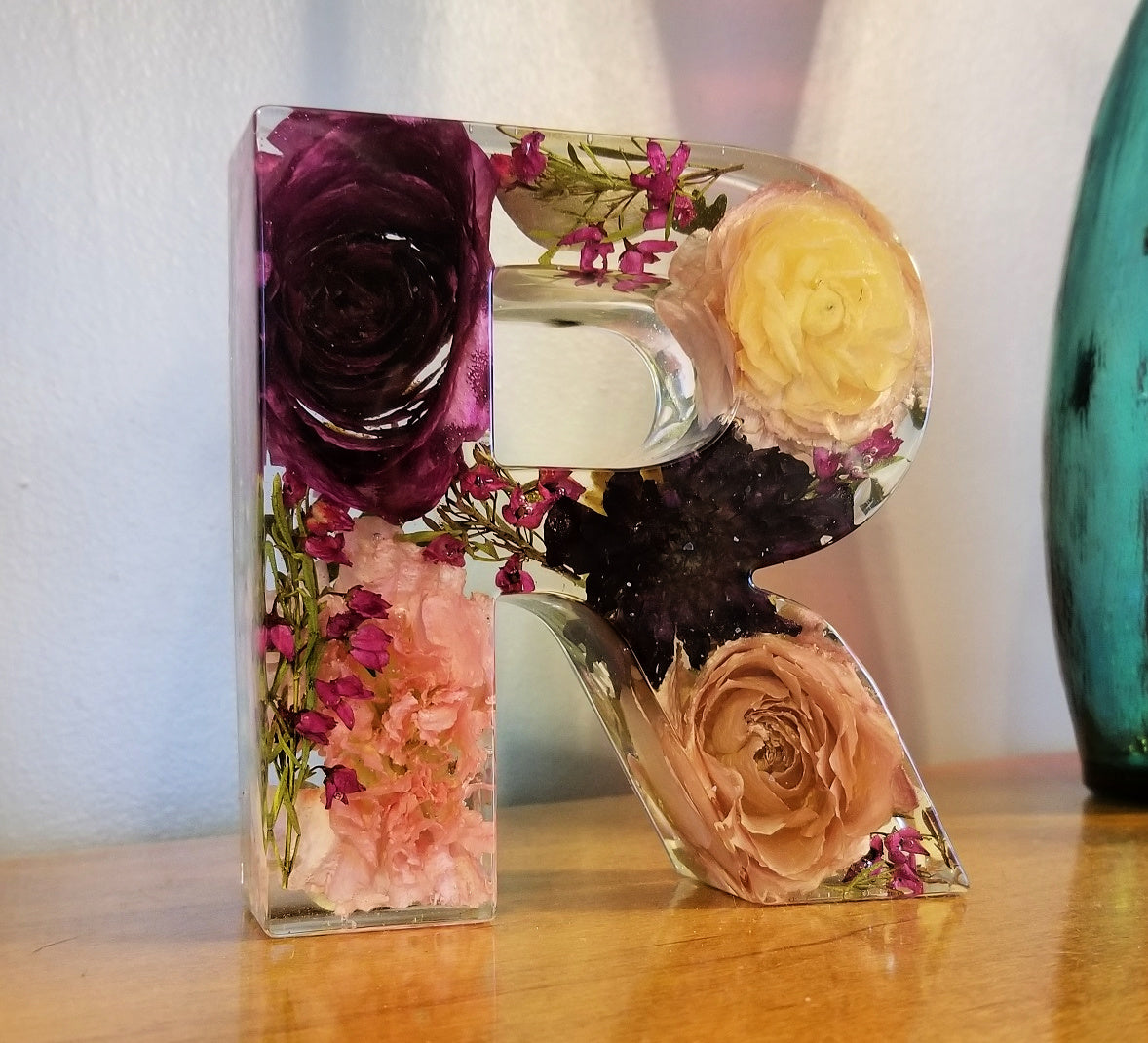 Clear resin letter R featuring preserved peach and red flowers from wedding or memorial bouquet, warm-toned floral keepsake