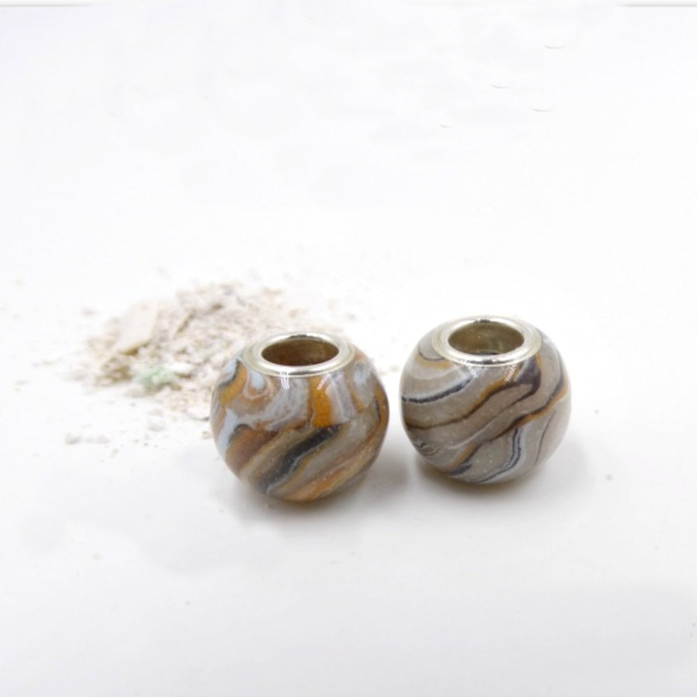 Two handcrafted pet memorial beads, designed to resemble a pet’s fur pattern, infused with cremation ashes for a lasting tribute.