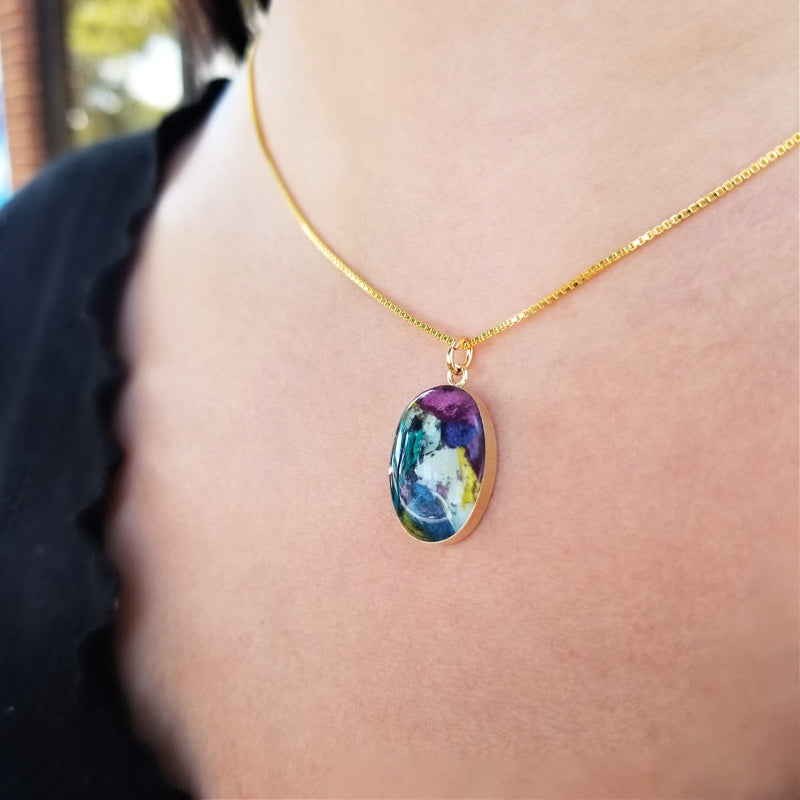 A model wearing the Gold Timeless Floral Keepsake pendant, a gold-filled memorial jewelry piece infused with preserved funeral flowers.