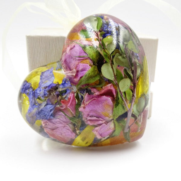 Large resin heart encased with colorful flower petals and lush greenery.