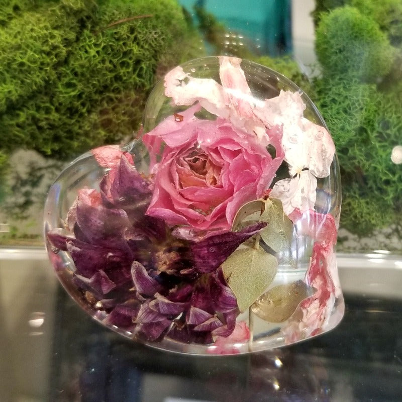 A resin heart filled with preserved pink flowers for a delicate look.