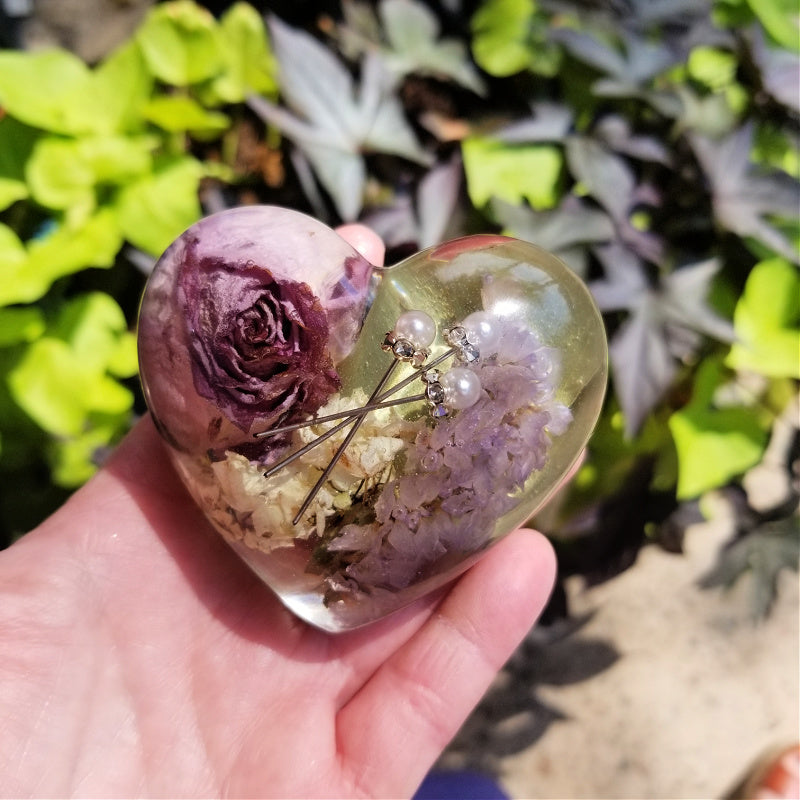 Large resin heart held by model, featuring flowers and sentimental bouquet pins.

