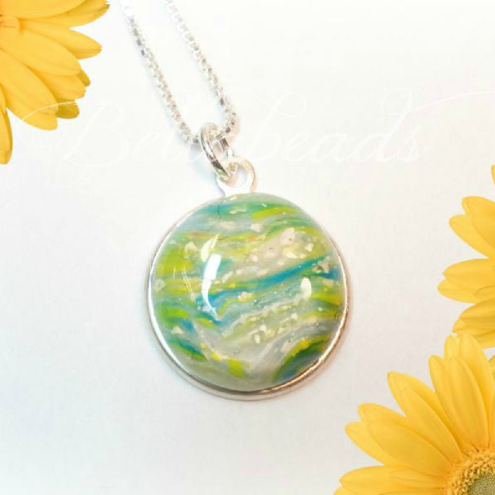 Sterling silver round pendant with a white, yellow, and green swirled  with ashes.