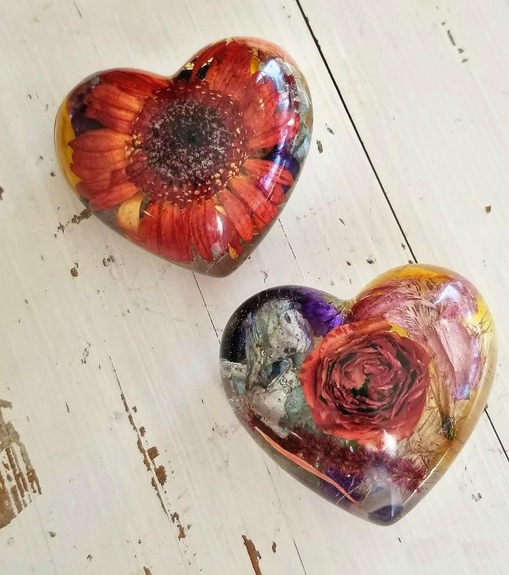 wo resin heart keepsakes side by side, featuring pressed flowers.

