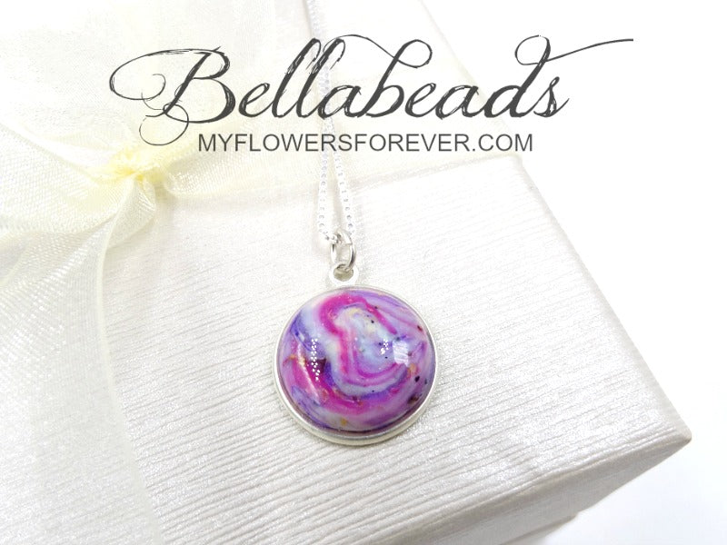 Sterling silver round pendant with a lavender, fuchsia, and white clay swirled with ashes.