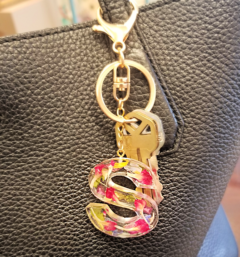 Resin letter S keychain with hot pink flowers hanging from purse, custom floral accessory